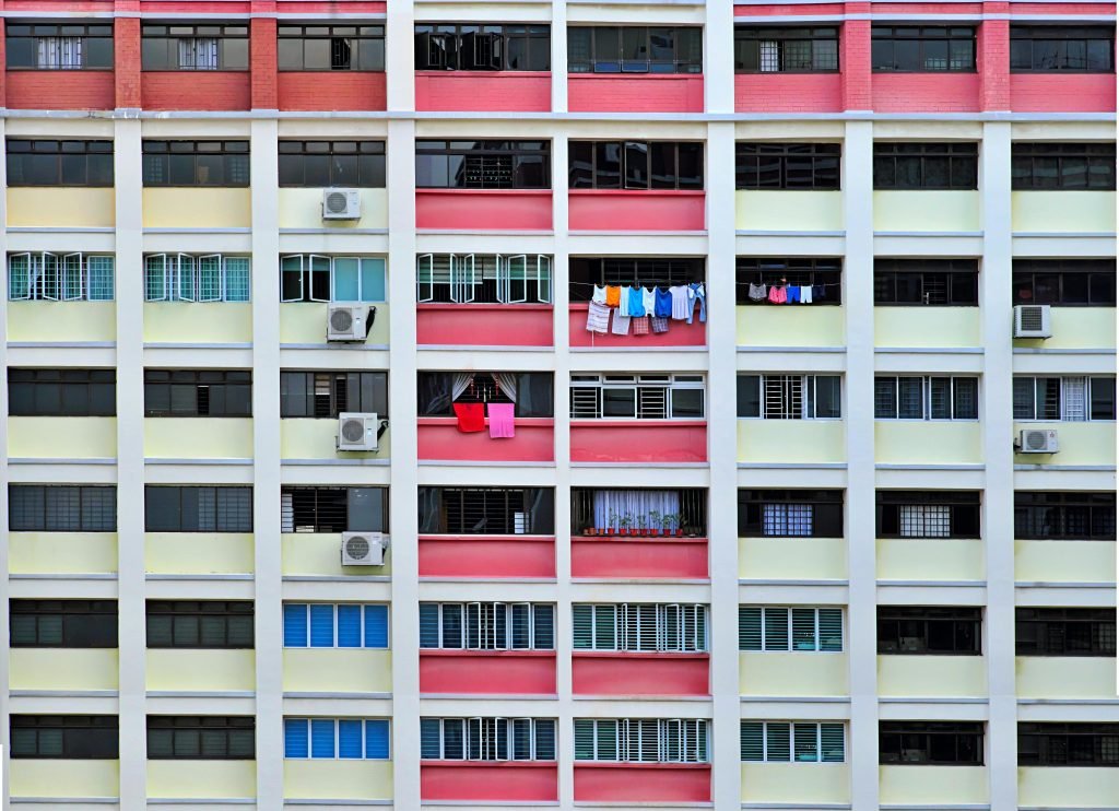 Vibrant apartment building facade featuring hanging laundry and air conditioning units.