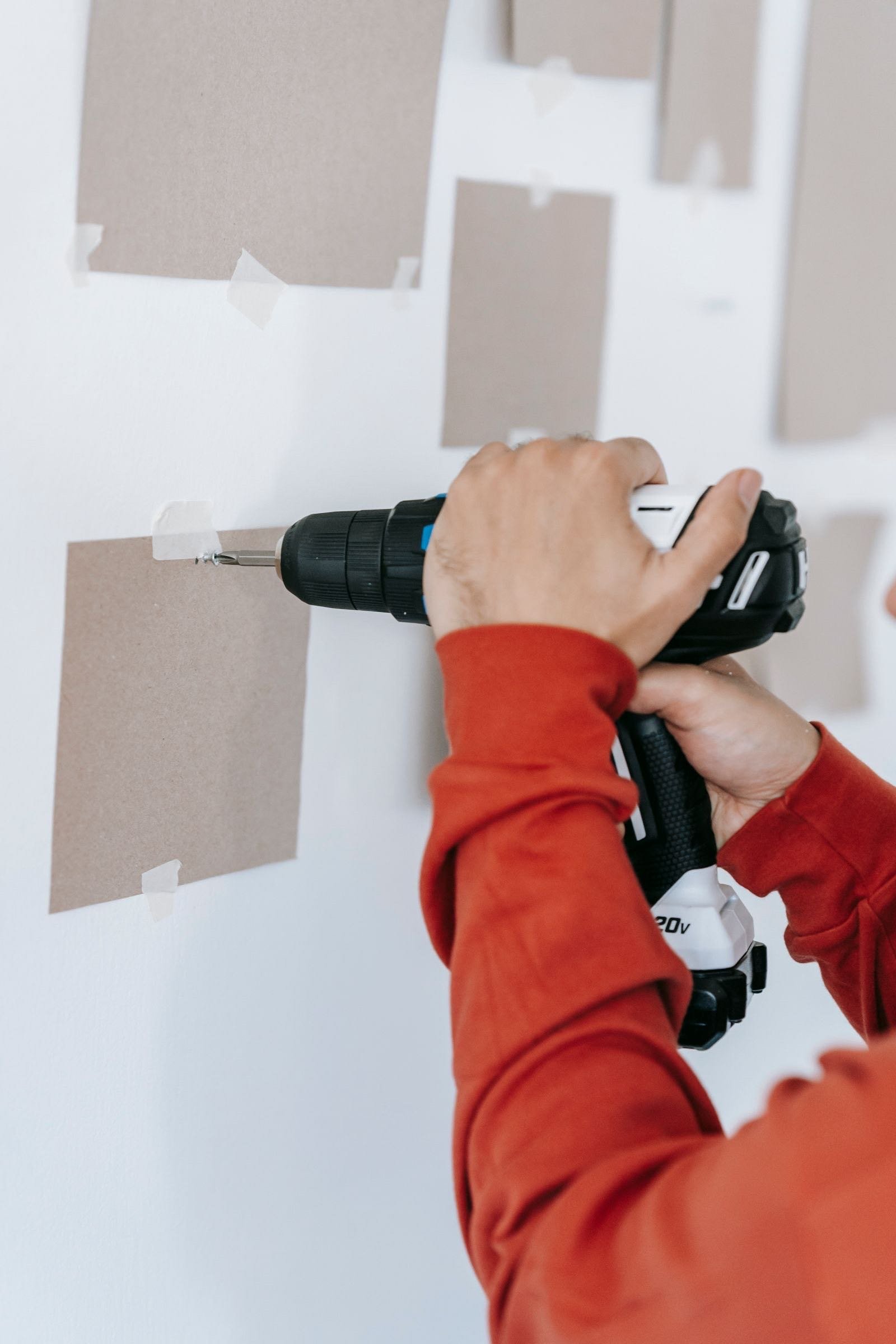 Hands drilling a screw into a wall