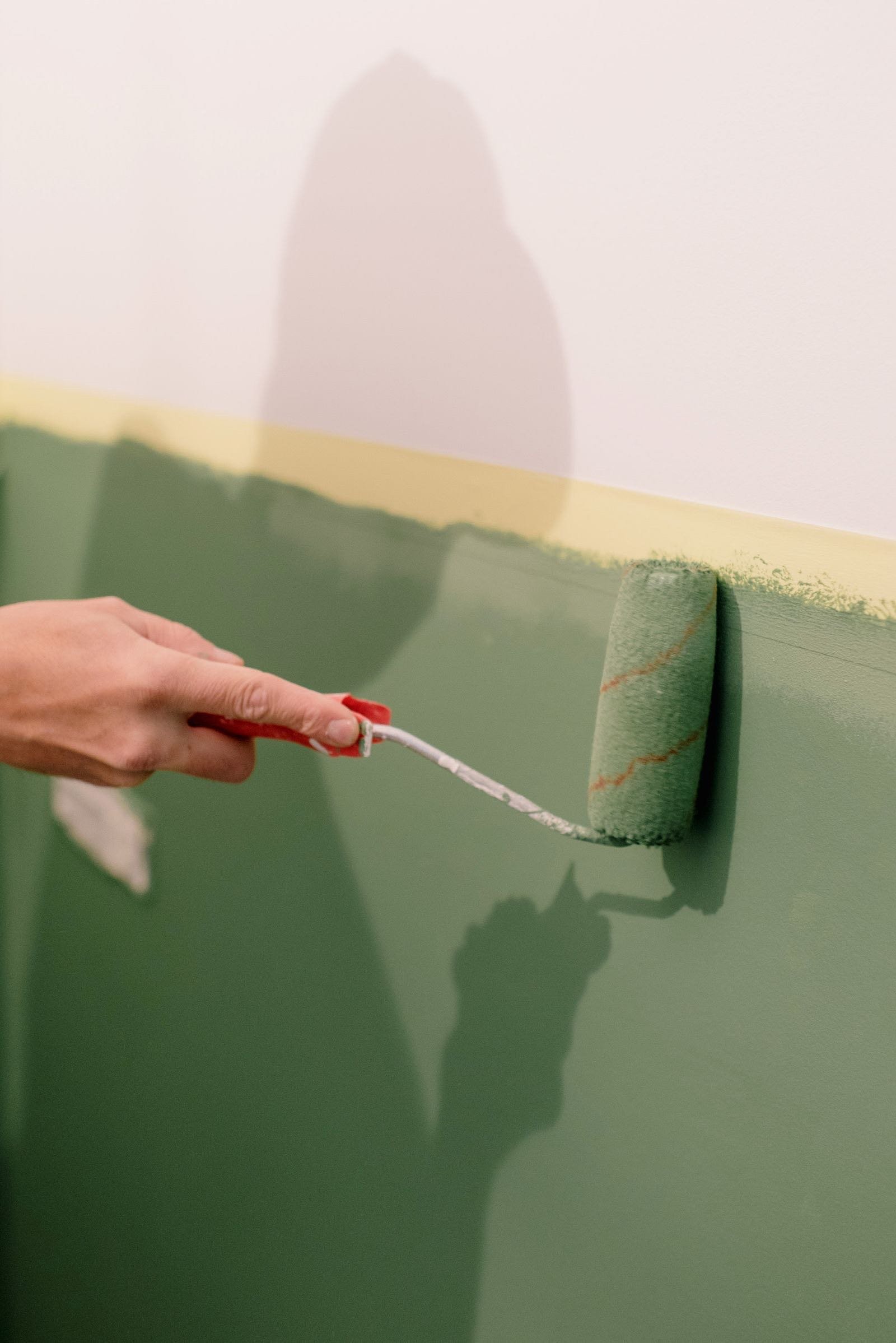 Paint roller applying green paint to a wall